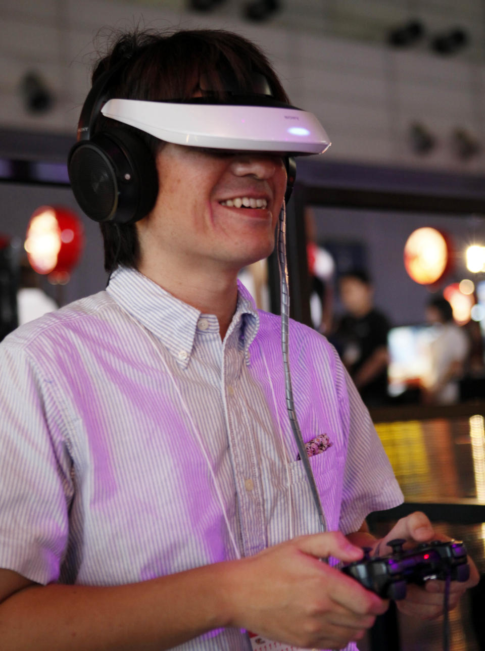 A visitor demonstrates Sony's head-mounted display HMZ personal 3D viewer, which provides a 3-D theater of music videos, movies and games, at the Tokyo Game Show in Makuhari, Chiba, near Tokyo,Thursday, Sept. 20, 2012. Some 200 companies take part in the annual gala exhibition which opens to the public on Sept. 22-23. (AP Photo/Koji Sasahara)