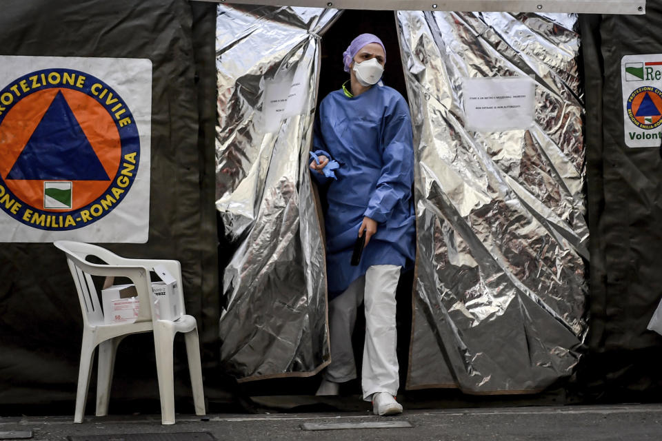 A paramedic wearing a mask gets out of a tent set up by the Italian Civil Protection outside the emergency ward of the Piacenza hospital, northern Italy, Thursday, Feb. 27, 2020. Italy is changing how it reports coronavirus cases and who will get tested in ways that could lower the country's caseload even as an outbreak centered in northern Italy spreads in Europe. (Claudio Furlan/Lapresse via AP)