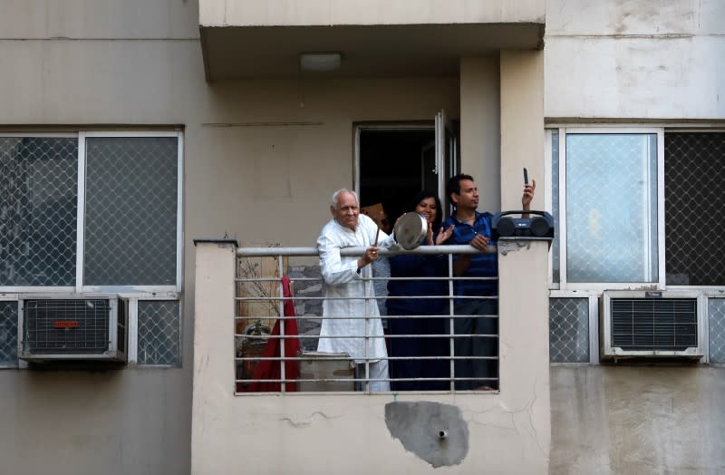 Residents clap and bang utensils from their balconies to cheer for emergency personnel and sanitation workers who are on the frontlines in the fight against coronavirus, in Noida