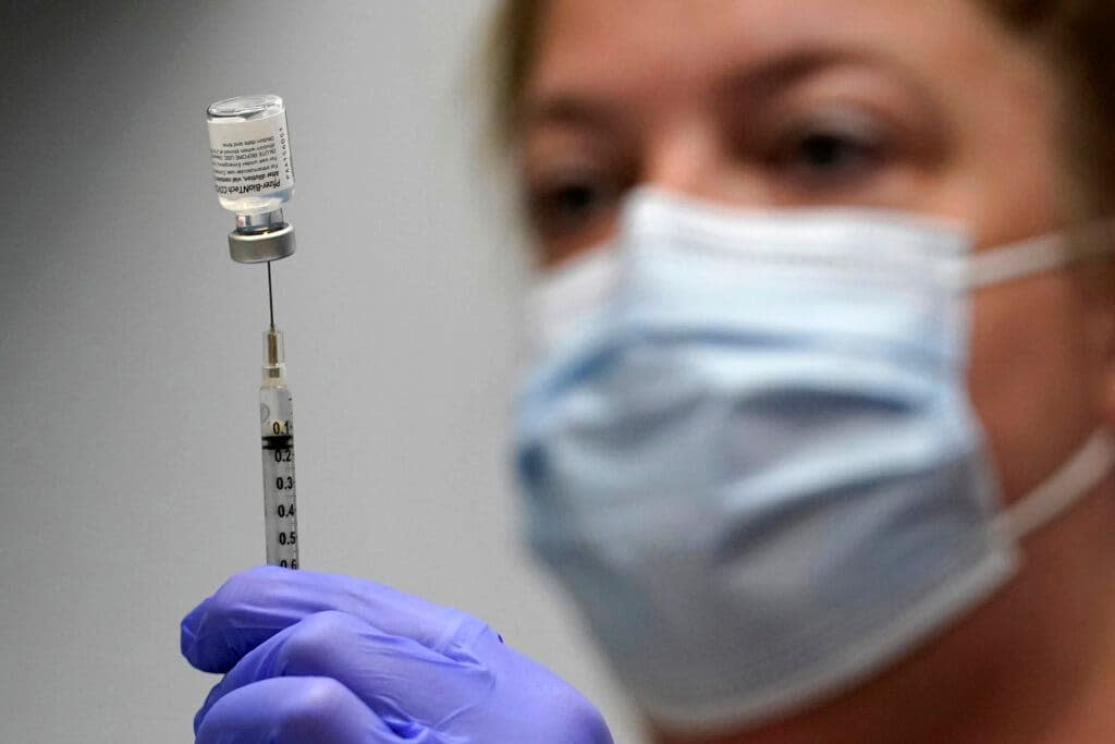 Hollie Maloney, a pharmacy technician, loads a syringe with Pfizer’s COVID-19 vaccine at the Portland Expo in Portland, Maine. (AP Photo/Robert F. Bukaty, File)