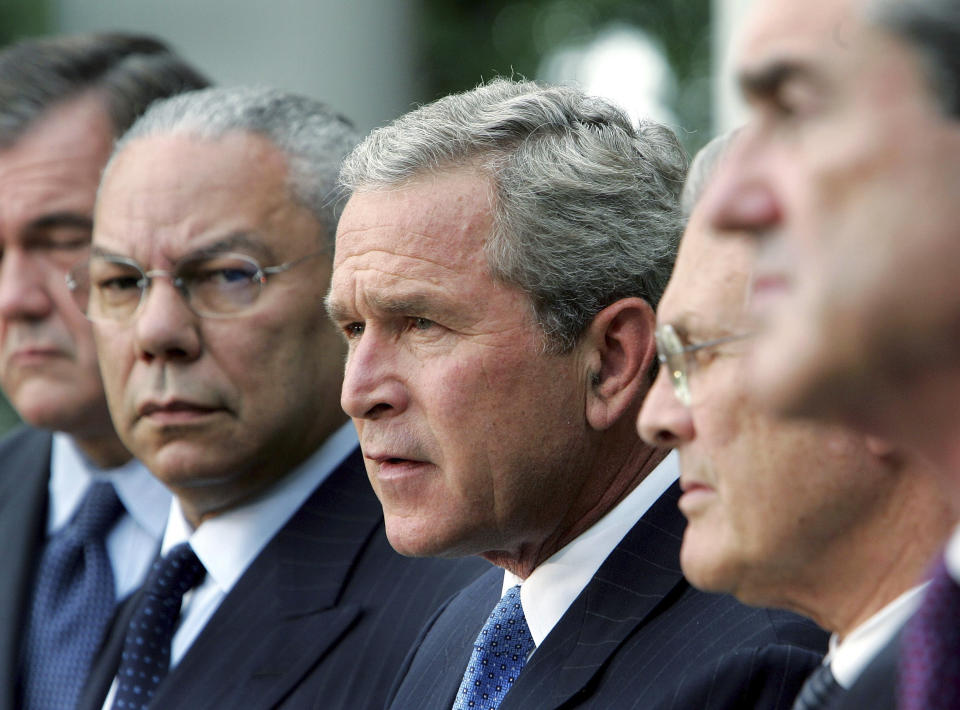 FILE - In this Aug. 2, 2004 file photo, President Bush, center, makes remarks in the Rose Garden of the White House, about his plans to implement the Sept. 11. Commission's recommendation to create a national intelligence director. Left to right Secretary of Homeland Security Tom Ridge, Secretary of State Colin Powell, Bush, Secretary of Defense Donald H. Rumsfeld, and FBI Director Robert Mueller. Powell, former Joint Chiefs chairman and secretary of state, has died from COVID-19 complications. In an announcement on social media Monday, the family said Powell had been fully vaccinated. He was 84. (AP Photo/Ron Edmonds)