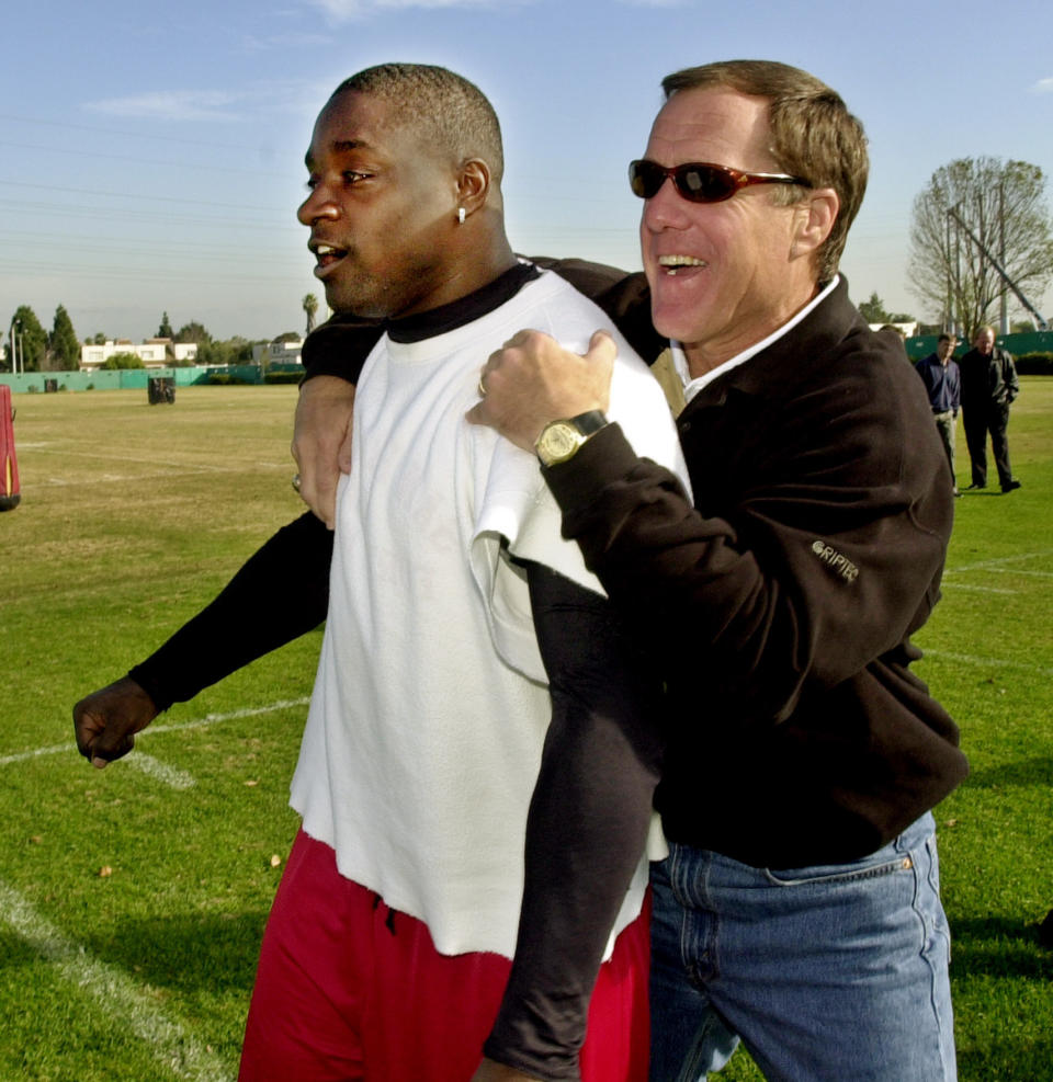 FILE - In this Thursday, Jan. 10, 2002, file photo, San Francisco 49ers running back Garrison Hearst, left, is congratulated by 49ers general manager Terry Donahue during practice at the 49ers training camp in Santa Clara, Calif., as Hearst won The Associated Press NFL Comeback Player of the Year Award. Donahue, the winningest coach in Pac-12 Conference and UCLA football history who later served as general manager of the NFL’s San Francisco 49ers, died Sunday, July 4, 2021. He was 77. (AP Photo/Paul Sakuma, File)