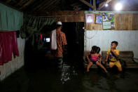 A man walks inside his house as it floods with sea water during high tide in Sriwulan village in Demak, Indonesia, January 30, 2018. REUTERS/Beawiharta