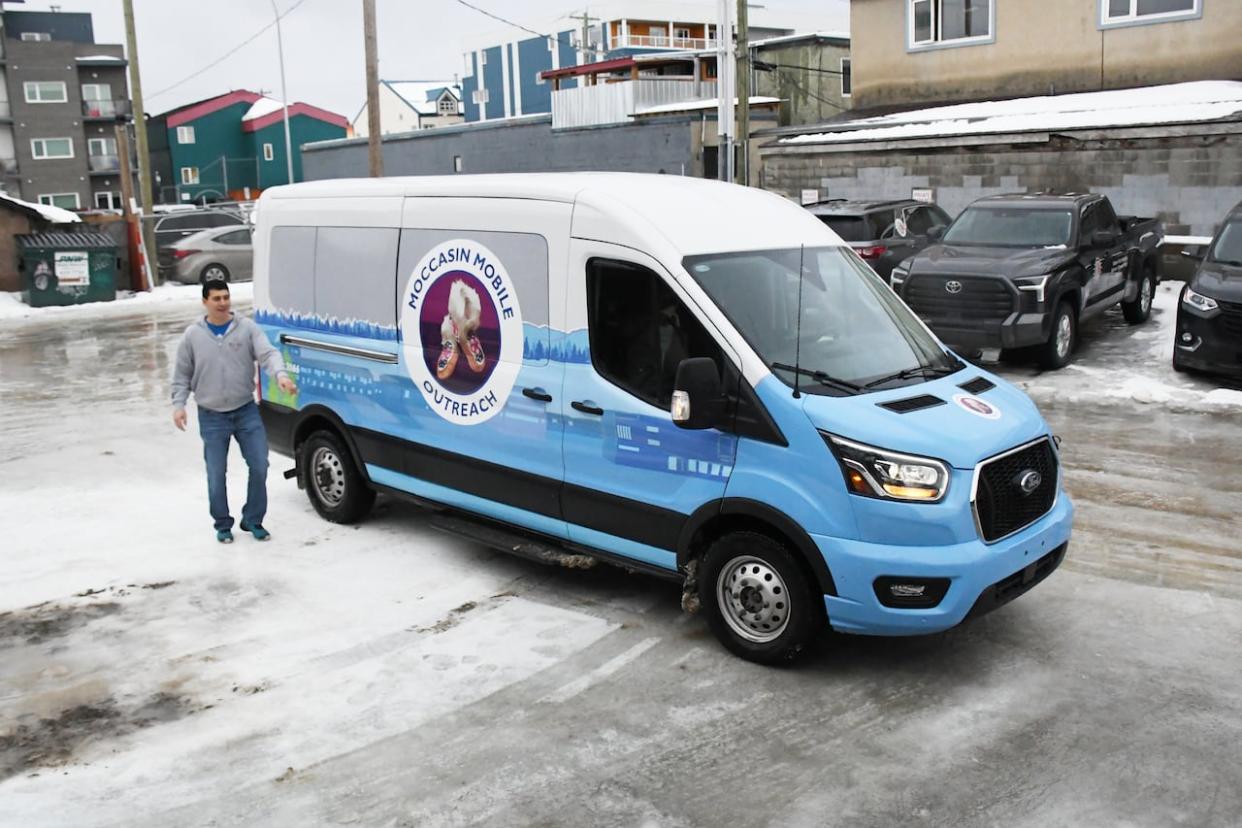 Moccasin Mobile Outreach coordinator Phil Harry stands next to the program's new van on Monday. The initiative, run by the Council of Yukon First Nations, will see staff drive around downtown Whitehorse and offer support for vulnerable Yukon First Nations and Indigenous people.  (Jackie Hong/CBC - image credit)