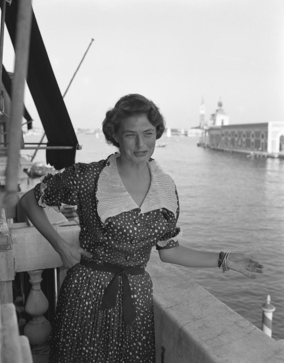 Bergman, wearing a polka-dotted dress, portrayed while posing on a terrace with the Canal Grande in the background, in Venice.