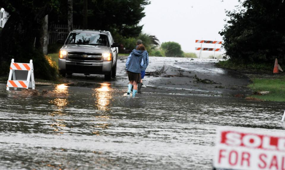 A pair of residents try to navigate a flooded street in Cedar Key, FL Thursday evening. 