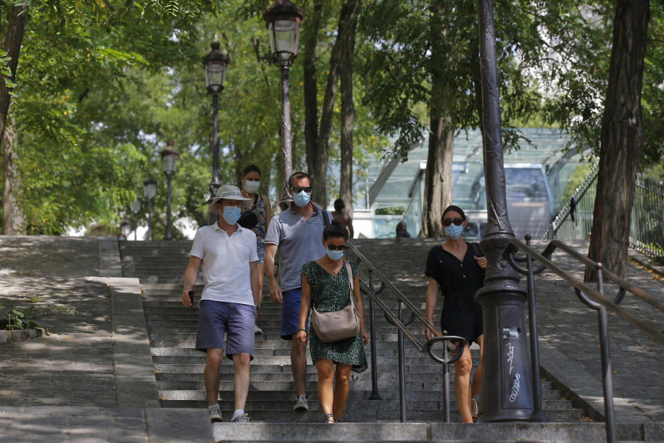 People walk down the stairs in the Montmartre district Monday, Aug. 10, 2020 in Paris. People are required to wear a mask outdoors starting on Monday in the most frequented areas of the French capital. The move comes as the country sees an uptick in virus infections. (AP Photo/Michel Euler)