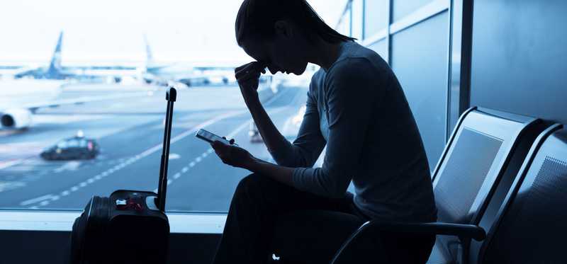 A passenger waiting with luggage in airport terminal.