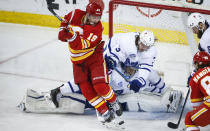 Toronto Maple Leafs' Justin Holl, right, crashes over goalie Frederik Andersen, center, trying keep Calgary Flames' Matthew Tkachuk from the puck during the second period of an NHL hockey game, Tuesday, Jan. 26, 2021 in Calgary, Alberta. (Jeff McIntosh/The Canadian Press via AP)