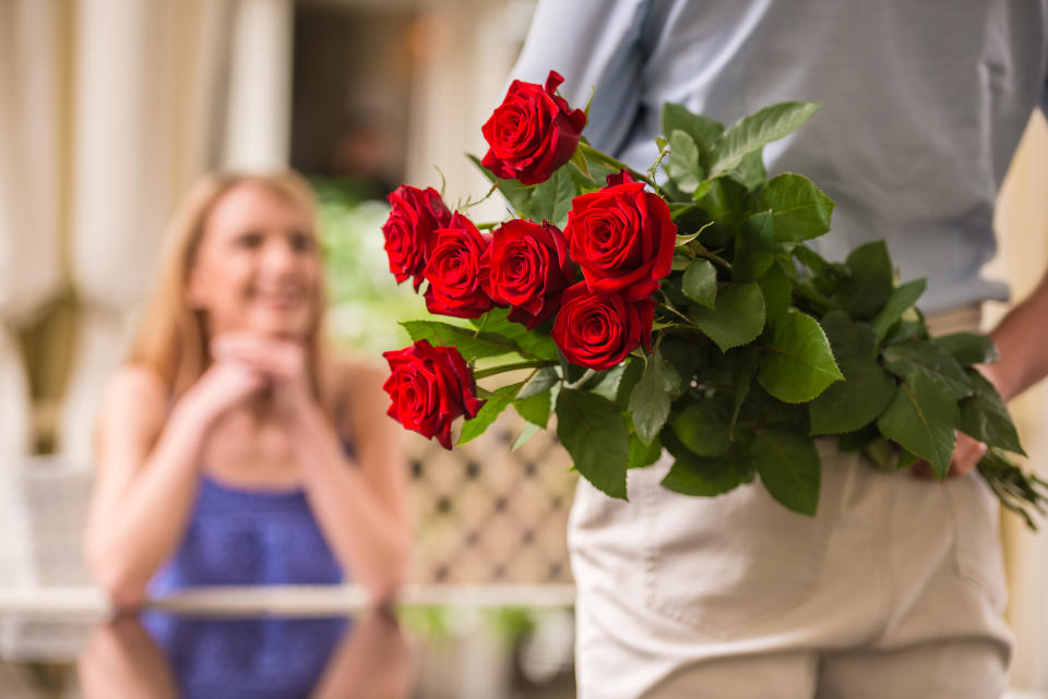 Man brings a bunch of roses to a woman