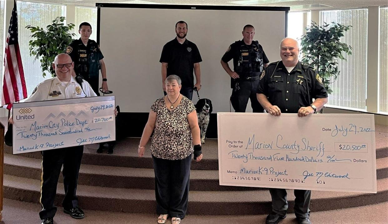 Major B.J. Gruber, left, from the Marion Police Department and Sheriff Matt Bayles, right, from the Marion County Sheriff's Office accept checks from Jill Chitwood, center, of the Marion K9 Project that will benefit each agency's K9 unit. Also shown are, from left to right, local K9 officers Deputy John Endicott, Det. Colin Lowe, and Deputy Sam Staley.
