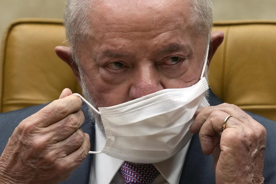 Brazil's President Luiz Inacio Lula da Silva removes his mask, following medical directives to avoid the possibility of contracting a respiratory illness before his scheduled operation, during a ceremony in the Supreme Court in Brasilia, Brazil, Thursday, Sept. 28, 2023. Lula is expected to undergo hip replacement surgery tomorrow morning at the Sirio-Libanes hospital in Brasilia. (AP Photo/Eraldo Peres)