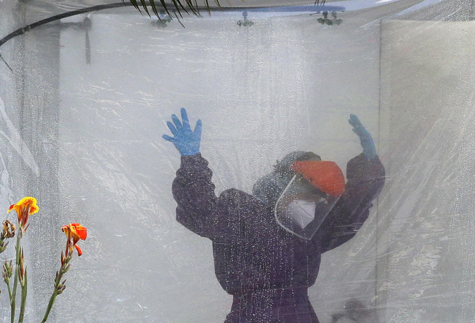 A health worker wearing a protective suit is disinfected inside a portable tent outisee the Gat Andres Bonifacio Memorial Medical Center during an enhanced community quarantine to prevent the spread of the new coronavirus in Manila, Philippines, Monday April 27, 2020. (AP Photo/Aaron Favila)