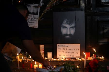 A man lights candles next to a portrait of Santiago Maldonado, a protester who went missing since security forces clashed with indigenous activists in Patagonia on August 1, 2017, placed at the entrance of a judicial morgue in Buenos Aires, Argentina October 20, 2017. REUTERS/Marcos Brindicci