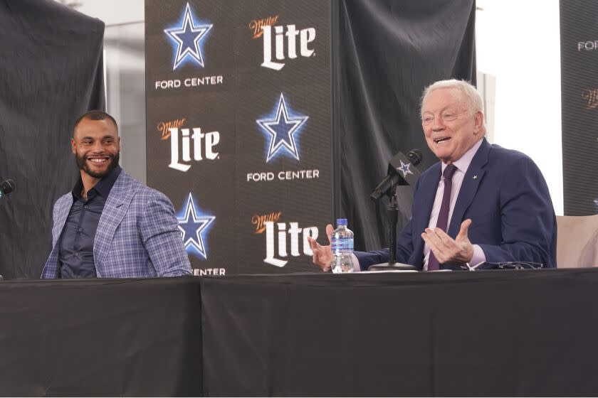 Dallas Cowboys quarterback Dak Prescott, left, looks on and smiles as team owner Jerry Jones speaks during a news conference.