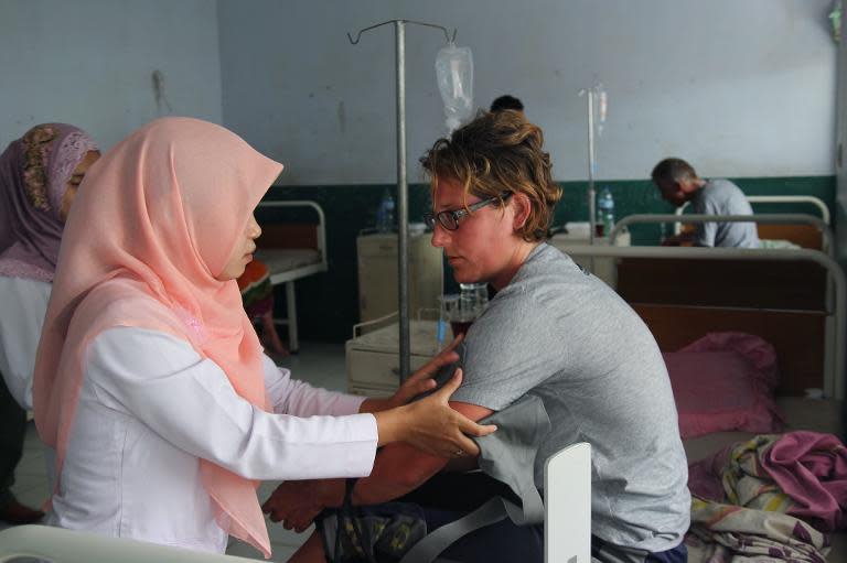 An unidentified female German survivor (R) is attended to by a nurse at a hospital in Sape, on Indonesia's eastern Sumbawa island, on August 18, 2014 following a rescue after a tourist boat carrying 25 sank during a storm