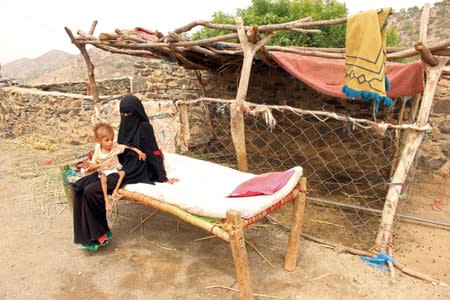 Grandmother of malnourished Muath Ali Muhammad sits with him on a bed outside their home in Aslam district of the northwestern province of Hajja