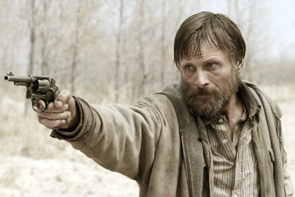 A bearded and disheveled Viggo Mortensen points a gun at someone