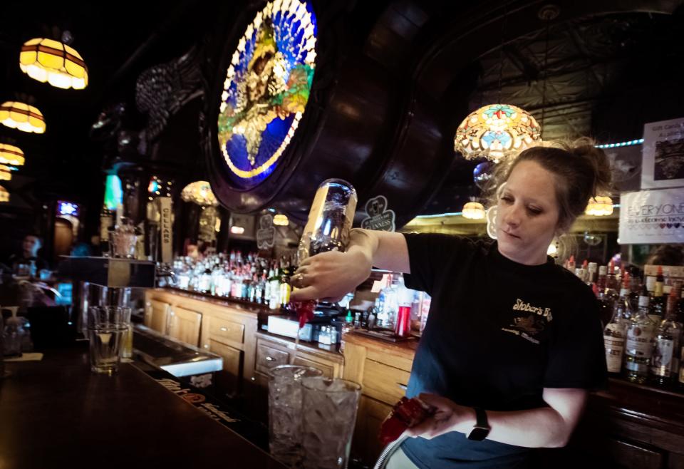 Lex Springsteen of Stober's Bar in Lansing pours drinks for patrons Monday evening, March 14, 2022.