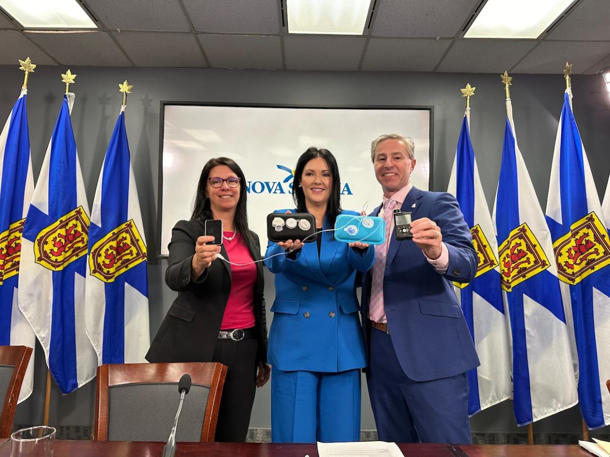 Health Minister Michelle Thompson, left, Maria Campbell of Diabetes Canada, and Premier Tim Houston hold up examples of the equipment the province is funding. (Taryn Grant/CBC - image credit)