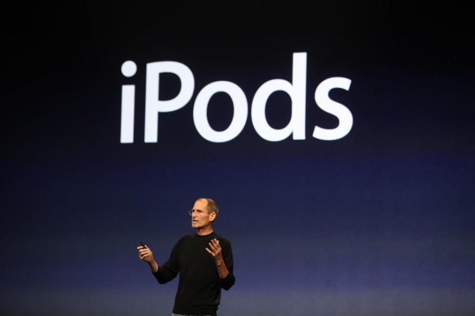 Steve Jobs onstage with the text "iPods" above him