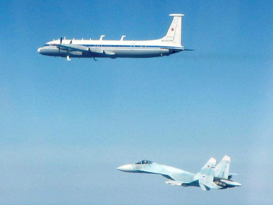 A Russian Il-22 flying next to a Su-27in a lightly cloudy sky.