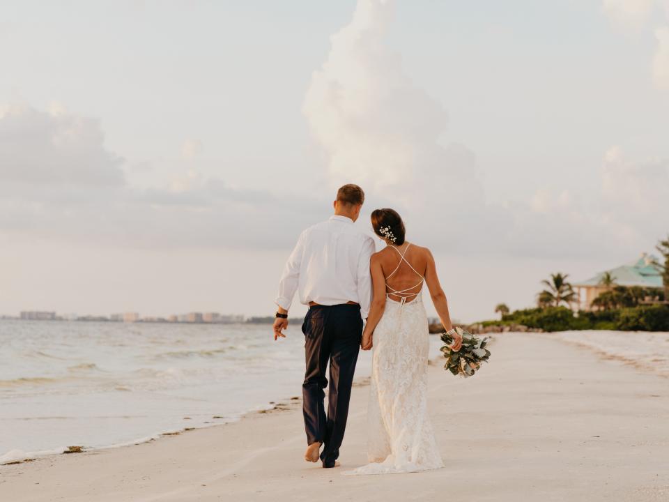 A married couple walks on a beach together