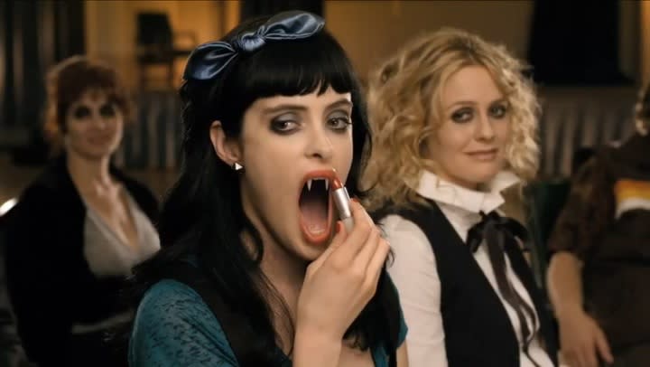 Krysten Ritter puts lipstick to her elongated, fanged mouth as Alicia Silverstone looks on in the 2012 film Vamps.