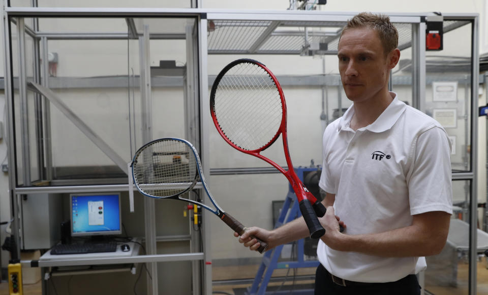 In this photo taken Friday June, 28, 2019, Jamie Caple-Davies, the head of the International Tennis Federation (ITF) science and technical department, holds up various designs of tennis racquets- both of which passed scrutiny by the ITF, at their lab in Roehampton, near Wimbledon south west London. Based for about 20 years in a three-room area on what used to be a pair of squash courts in Roehampton, the ITF tech lab is filled with more than $1 million worth of machines that help make sure rules are followed and parameters are met. (AP Photo/Alastair Grant)