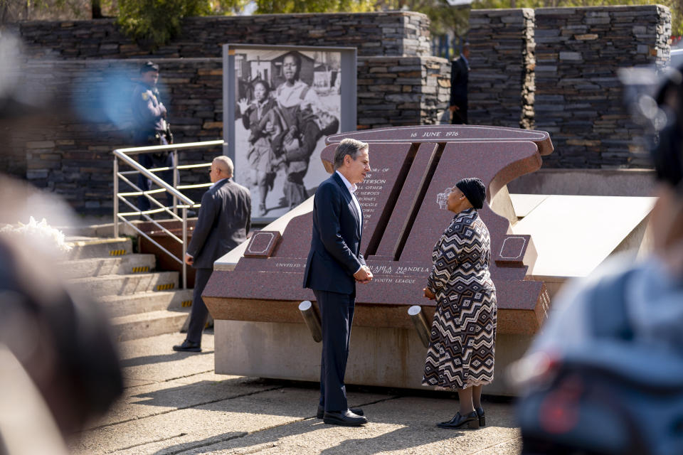 Secretary of State Antony Blinken, left, greets Antoinette Sithole, the sister of the late Hector Pieterson, as he visits the Hector Pieterson Memorial in Soweto, South Africa, Sunday, Aug. 7, 2022. Peaceful child protesters were gunned down by police 30 years ago in an attack that awakened the world to the brutality of the apartheid regime. At top, is an iconic picture of Antoinette, running with mouth open in a scream alongside a friend carrying the body of her slain brother, Hector. (AP Photo/Andrew Harnik, Pool)