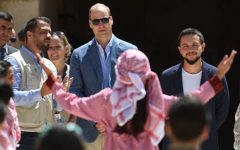 The Duke of Cambridge (centre) and Crown Prince Hussein of Jordan (right) watch a theatrical performance during a visit to the Jerash archaeological site  - Credit: Joe Giddens /PA