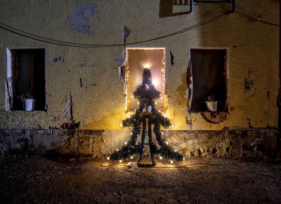 An illuminated Christmas tree leans against the window of a damaged house in Mayschoss in the Ahrtal valley, southern Germany, Tuesday, Dec.14, 2021. The region was hit by floodings exactly five months ago, causing the death of about 180 people. Amid the mud and debris still clogging the streets from last summer's devastating floods, residents of the Ahr Valley in western Germany are trying to spark some festive cheer with Christmas trees. (Photo/Michael Probst)