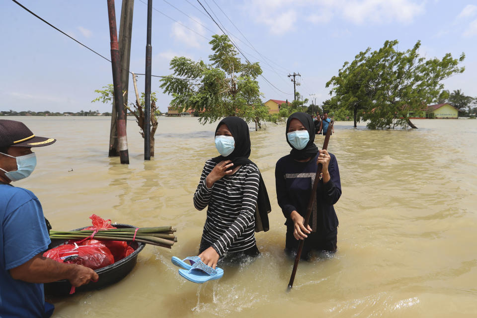 Indonesians carry their belongings as they wade through the water in a flooded neighborhood following heavy rains in Bekasi, Indonesia, Monday, Feb. 22, 2021. Thousands of residents are being evacuated on the outskirts of Indonesia’s capital amid flooding after the Citarum River embankment broke. (AP Photo/Achmad Ibrahim)