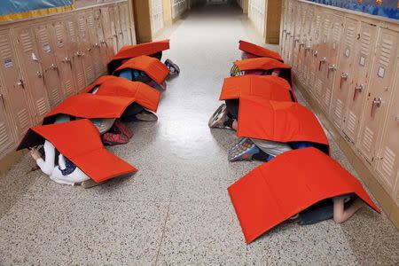 Children shield themselves using the "Body Guard" blanket in this undated handout illustration picture provided by ProTechtusa. REUTERS/ProTechtusa/Handout via Reuters