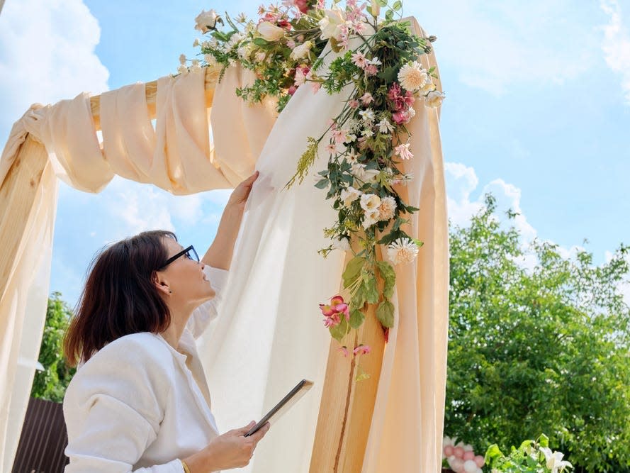 wedding coordinator fixing wedding arch