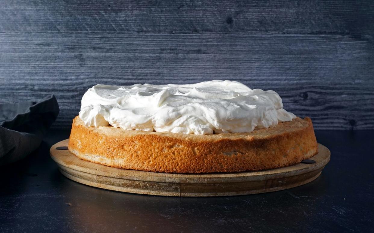 adding a thick layer of whipped cream for Swiss Pastry Shop black forest cake