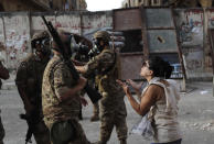 An anti-government protester, reacts in front of Lebanese soldiers during a protest against the political elites and the government, in Beirut, Lebanon, Saturday, Aug. 8, 2020. A group of Lebanese protesters including retired army officers have stormed the Foreign Ministry building in the capital Beirut as part of protests following the massive explosion this week. (AP Photo/Hussein Malla)