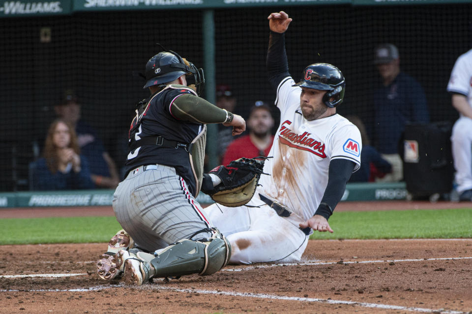 Cleveland Guardians' David Fry, right, scores ahead of the tag by Minnesota Twins' Christian Vazquez during the fifth inning of a baseball game in Cleveland, Saturday, May 18, 2024. (AP Photo/Phil Long)