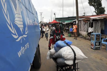 A resident of West Point neighbourhood, which has been quarantined following an outbreak of Ebola, pushes a wheelbarrow full of food rations from the United Nations World Food Programme (WFP) in Monrovia August 28, 2014. REUTERS/2Tango