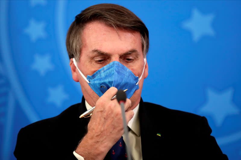 FILE PHOTO: Brazil's President Jair Bolsonaro adjusts his protective face mask at a press statement during the coronavirus disease (COVID-19) outbreak in Brasilia