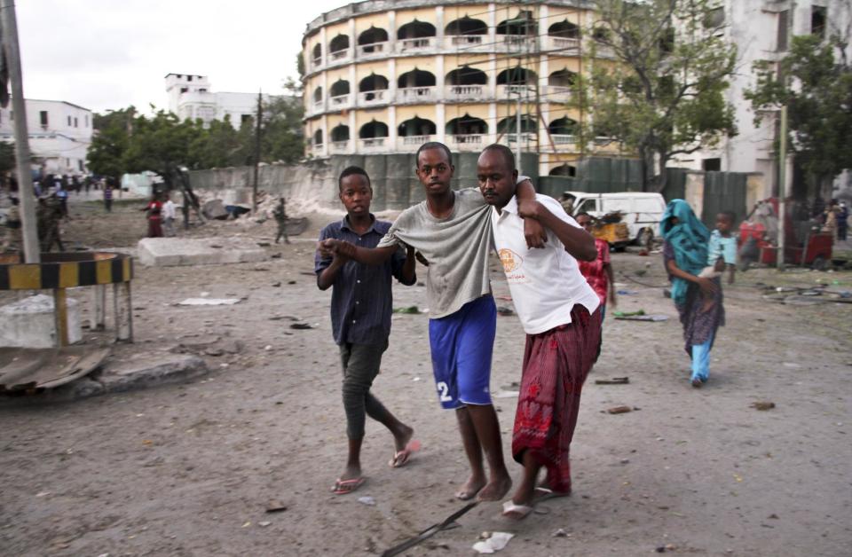 An injured man is assisted after a suicide car bomb attack that targeted a check point in Mogadishu, Somalia, Tuesday, March 21, 2017. The car bomb exploded Tuesday at a military checkpoint near Somalia's presidential palace in the capital after soldiers tried to stop the car and the bomber tried to speed through the checkpoint, killing a number of people, police said. (AP Photo/Farah Abdi Warsameh)