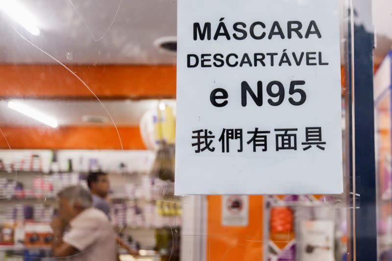 A sign indicating respirator masks are available in Portuguese and Chinese is displayed on the facade of a store in Sao Paulo