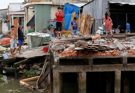 Men stand at their collapsed houses damaged by landslide along Mekong river in Can Tho city, Vietnam December 17, 2018. Picture taken December 17, 2018. REUTERS/Kham