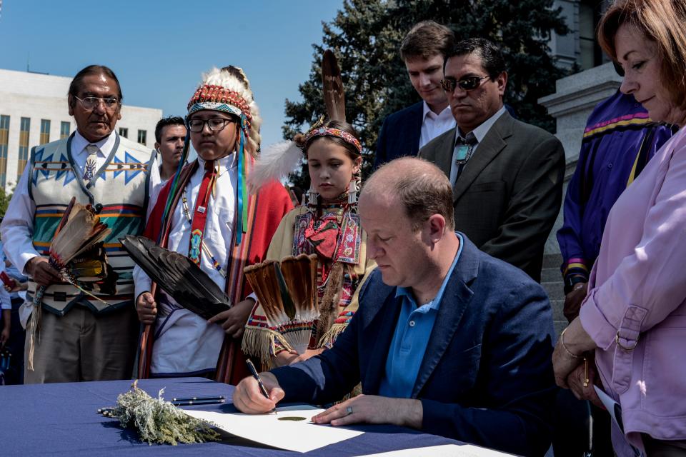 Colorado Gov. Jared Polis signs an executive order that rescinds proclamations from Colorado Territorial Gov. John Evans in 1864, at the Capitol in Denver, Colo. on Tuesday, Aug. 17, 2021.