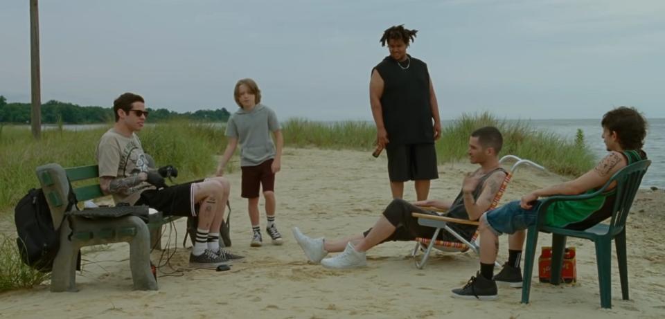 pete davidson, a child, and other castmates on the beach in "the king of staten island"