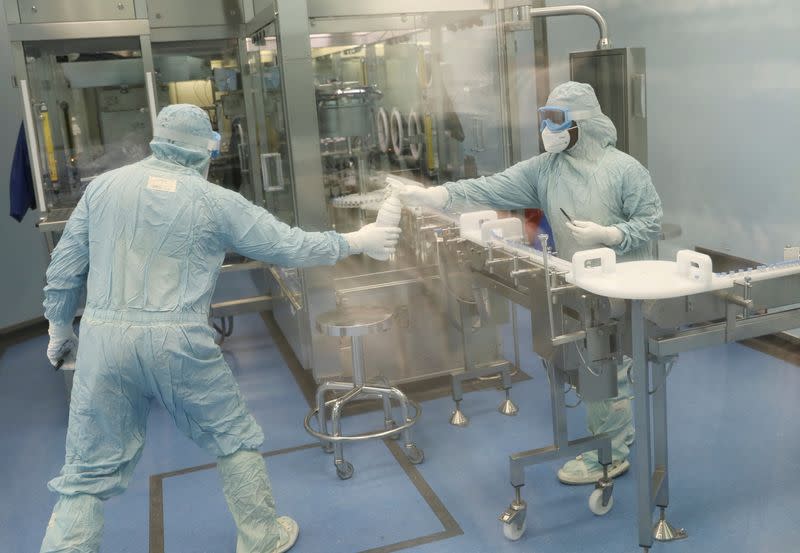 FILE PHOTO: Workers at South African pharmaceutical major Aspen Pharmacare facility pass a bottle, in Gqeberha