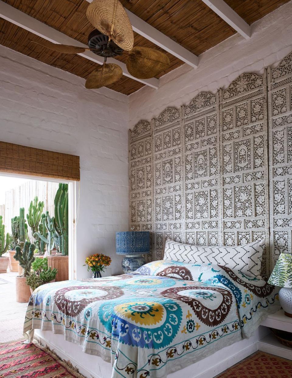 bedroom with a repurposed screen from india serving as the headboard