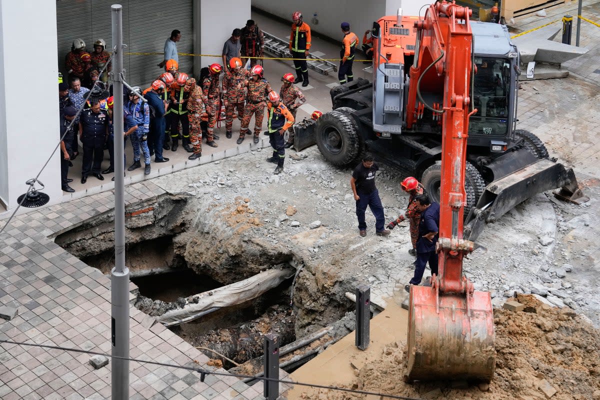 Fire and rescue department carry out search operations after a woman fell into a sinkhole in Kuala Lumpur on 23 August (AP)