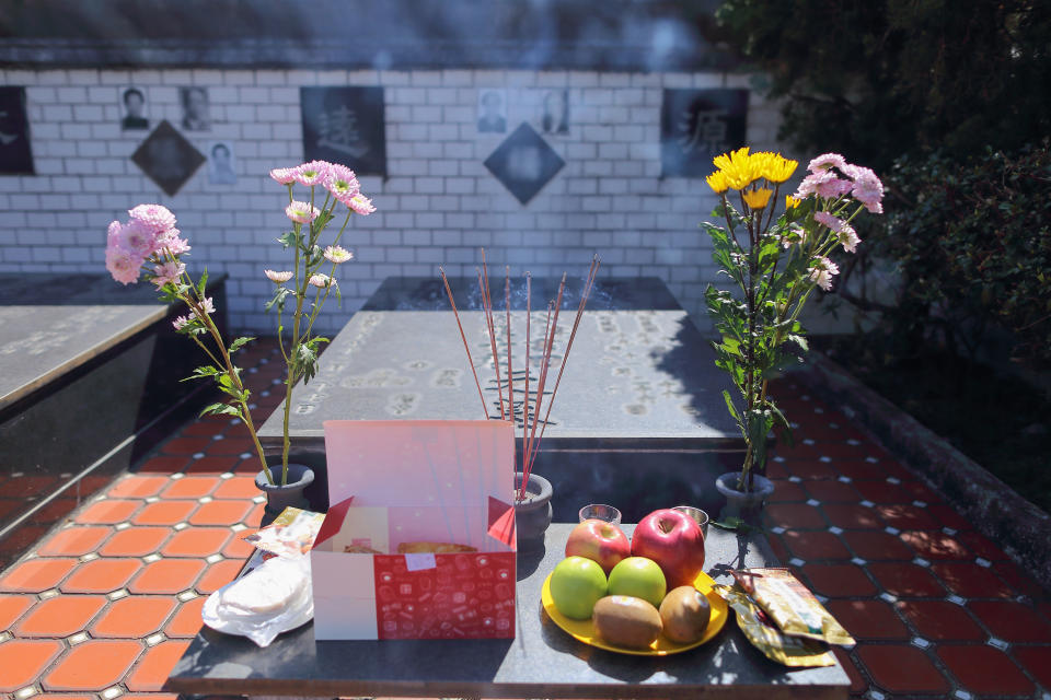 Offerings, bouquets of flowers and burning incense in front of the grave