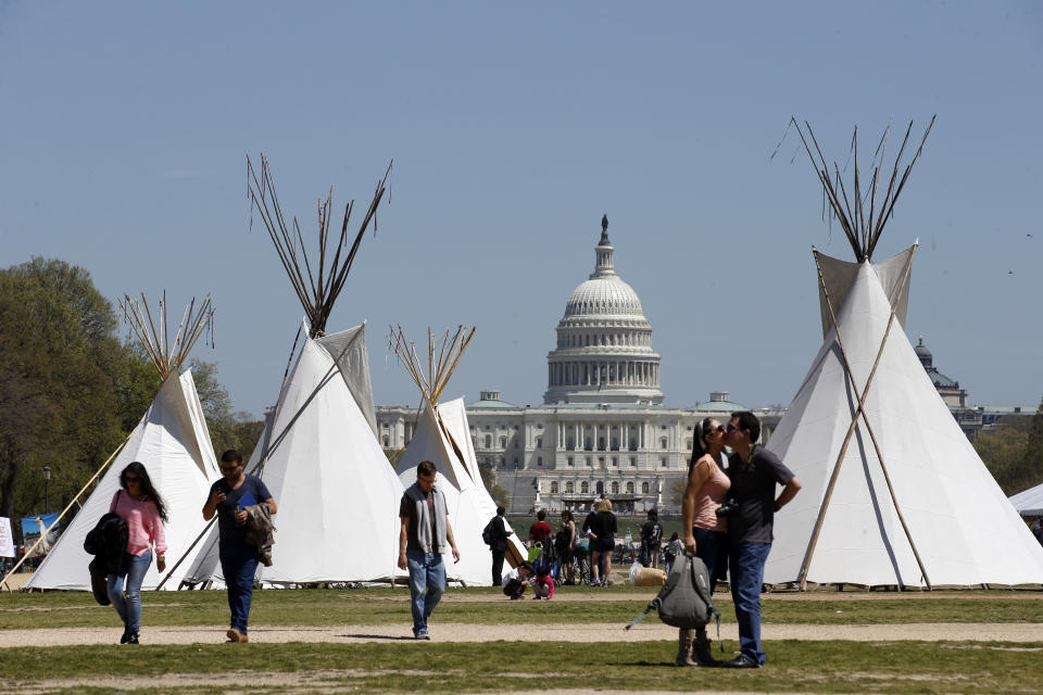 FILE - In this April 21, 2014, file photo, people walk near teepees set up on the National Mall in Washington, looking toward the Capitol. Days after President Barack Obama touted executive actions aimed at increasing energy efficiency, a bill with similar goals is expected to fall victim to partisan gridlock in the Senate. A bipartisan bill to promote many of the same efficiency goals Obama touted May 9 in California is expected to go down in defeat May 12 amid a dispute over the Keystone XL oil pipeline. (AP Photo/Alex Brandon, File)